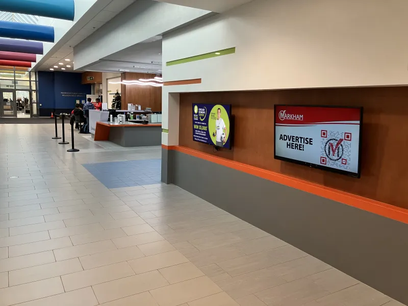 Digital screen with advertisements displayed in community centre.