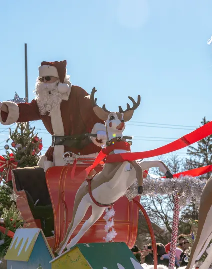 Santa Claus on parade float waving to crowd.