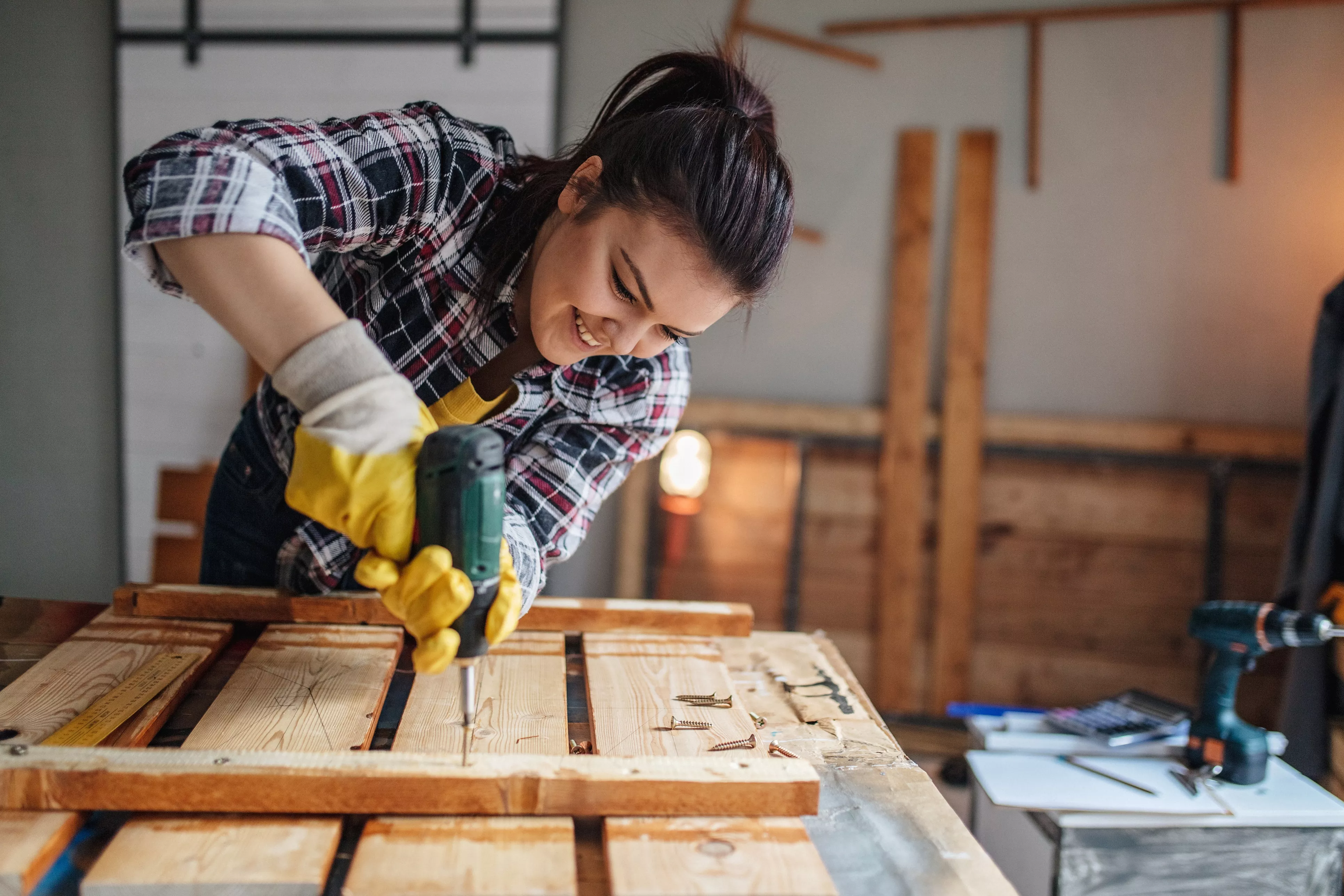 Person using a power tool to drill a nail into a wooden project.