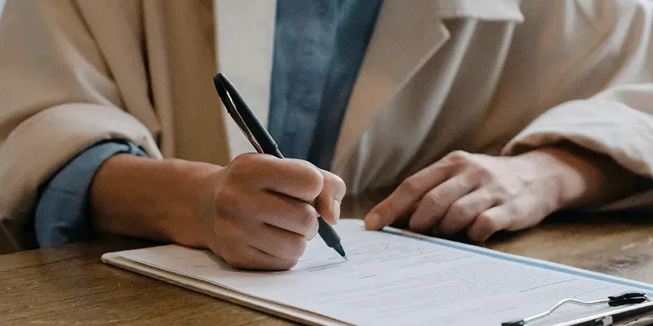 Professionally dressed person writing on paper.