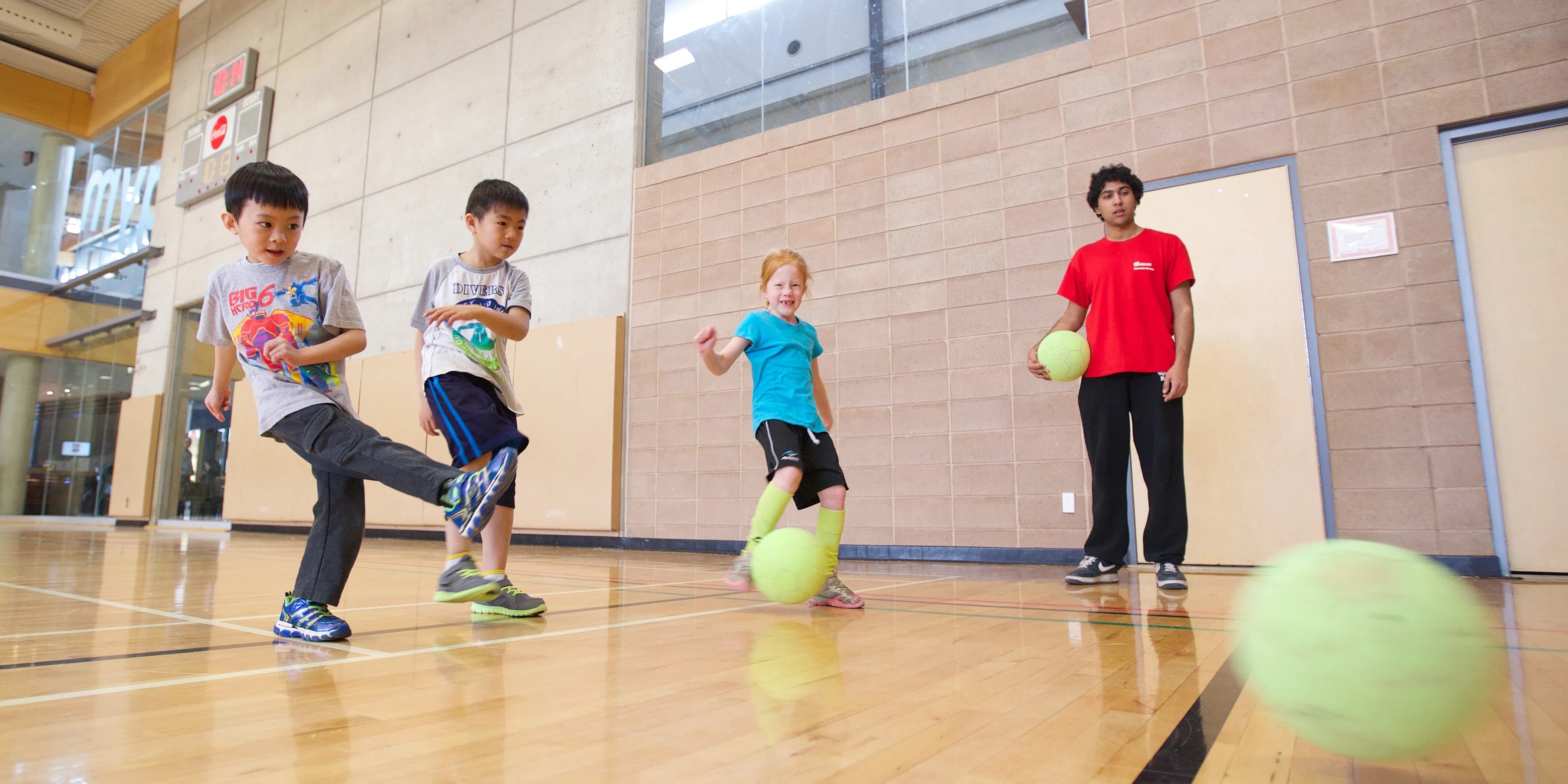 Camp staff playing kick ball with children.