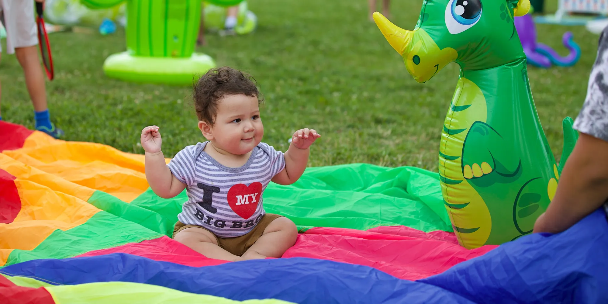 Baby playing on an outdoor mat with a blow up toy.